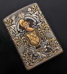 a lighter that is sitting on top of a black surface with gold and silver designs