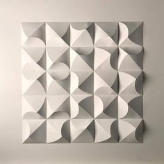 an abstract wall sculpture made out of white and grey paper with geometric shapes on it