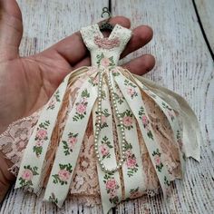 a hand holding an ornament in the shape of a dress with flowers on it