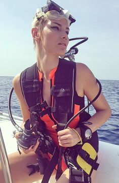 a woman wearing scuba gear on a boat in the ocean with her camera attached to her chest