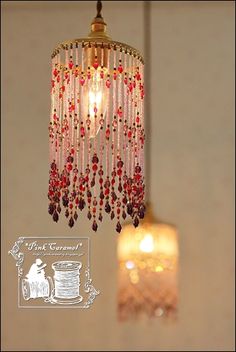 a chandelier hanging from the ceiling with red beads on it and a light bulb