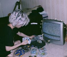 a woman sitting on the floor next to a tv
