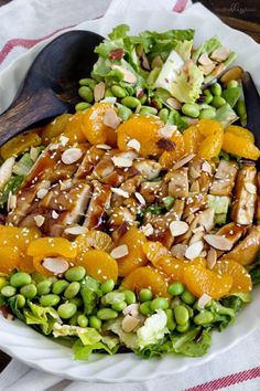 a salad with oranges, peas and almonds in it on a white plate