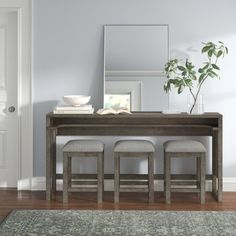 a dining room table with four stools and a mirror on the wall above it