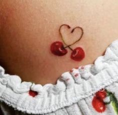 a small cherry tattoo on the back of a woman's stomach, with two cherries in the shape of a heart