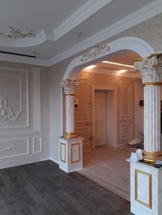 an empty room with white walls and gold trim on the columns, wood flooring