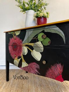 a painted dresser with flowers and plants on it