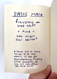 a hand holding an open book with writing on it that says basic math focusing on good stuff = time = you might feel better