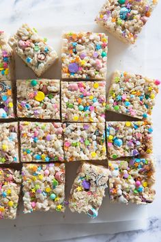 rice krispy treats are arranged on a white plate with sprinkles and candies