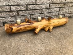 a piece of wood that has some candles in it on the ground next to a brick wall