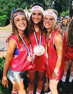 three girls in red shirts and headbands posing for the camera with their medals