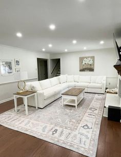 a large living room with white furniture and wood flooring is pictured in this image