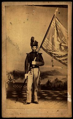 an old black and white photo of a man in uniform with a flag on his shoulder