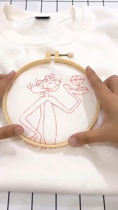 someone is stitching an embroidered pink cartoon character