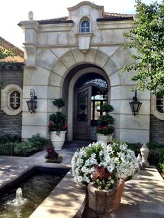 a large potted planter filled with flowers in front of a home entrance and water fountain