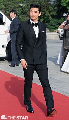 a man in a tuxedo is standing on a red carpet and posing for the camera