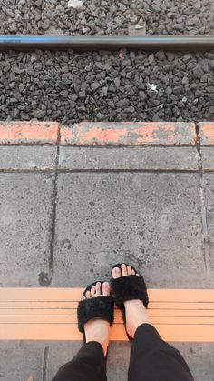 a person standing on a bench with their feet propped up against the ground next to a train track