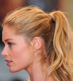 a close up of a woman with blonde hair wearing a pony tail ponytail and looking off to the side