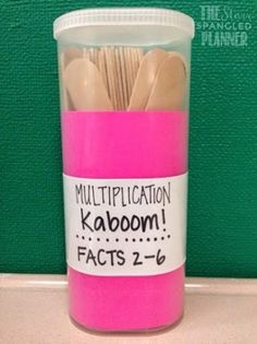 there is a pink cup with wooden spoons in it and the words multiplication kaboom fact 2 - 6