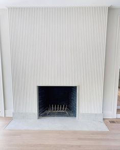 an empty room with a fireplace and white walls
