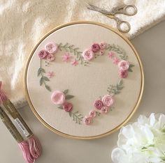 a close up of a heart shaped embroidery on a table with scissors and yarn next to it