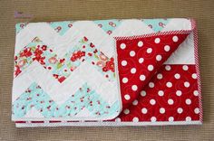 two quilted placemats sitting on top of each other, one red and the other white