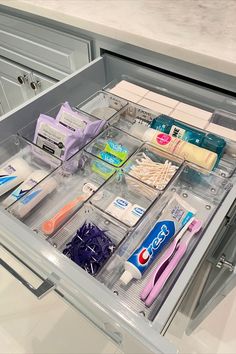 an open drawer in a kitchen filled with toothbrushes and other hygiene products, including toothpaste