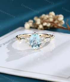 an oval cut blue topazte and diamond ring with side stones on a card