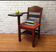 a wooden chair sitting next to a small table with books on it and an apple