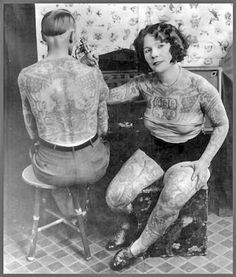 an old black and white photo of two people with tattoos