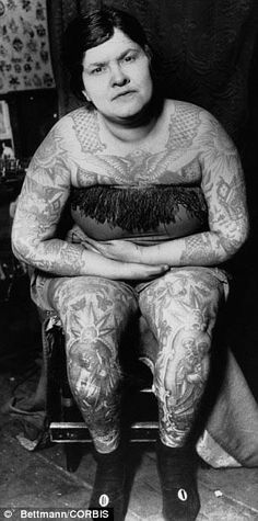 a woman sitting in a chair with tattoos on her body