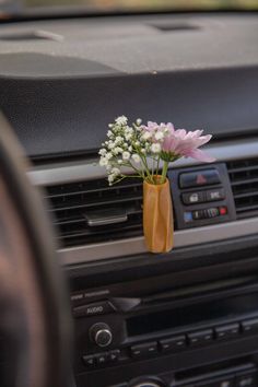 a car dashboard with flowers in a vase on the dash board, and an air vent