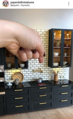 a hand reaching for something on top of a black cabinet