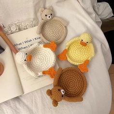 four crocheted ducks are sitting on a bed next to a book and pen