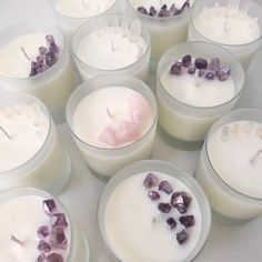 several candles with amethyst crystals in them sitting on a white counter top next to each other