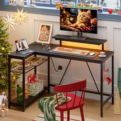 a computer desk with a christmas tree in front of it and pictures on the wall