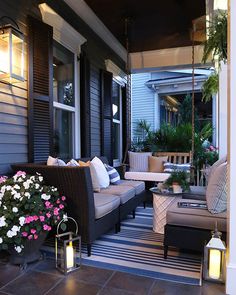 the porch is decorated with outdoor furniture and potted flowers on the table, along with hanging lanterns