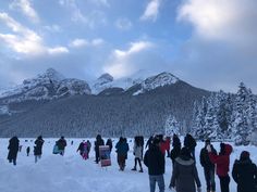 a group of people standing on top of snow covered ground in front of a mountain