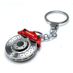 a close up of a metal object on a white surface with a keychain