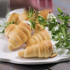 croissants with cream cheese and parsley are on a white platter