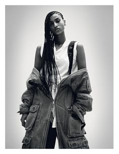 a black and white photo of a woman with dreadlocks wearing an oversize denim jacket