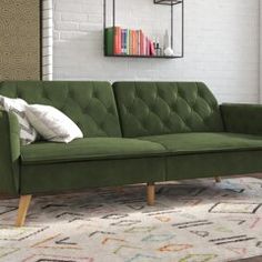 a green couch sitting on top of a rug in front of a white brick wall