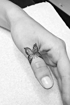 a woman's hand with a small butterfly tattoo on the left thumb and finger