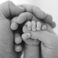 a hand holding a baby's finger with the words we're a family, we stick together