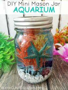 a mason jar filled with different types of sea creatures and sand in it, sitting on top of a wooden table