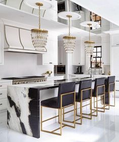 an elegant kitchen with marble counter tops and gold chandelier hanging from the ceiling