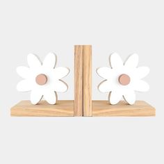 two white flower bookends sitting on top of a wooden shelf next to each other