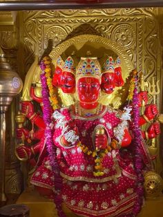 an idol is displayed in front of a gold wall with red and white decorations on it