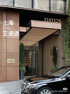 a black car parked in front of a tall brown building with chinese writing on it