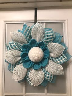 a blue and white wreath hanging on the front door with burlocked fabric flowers